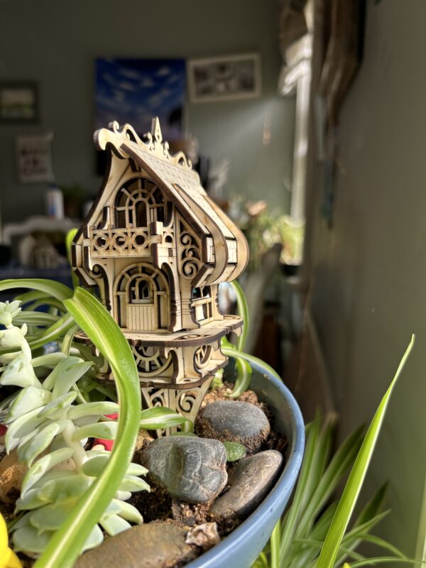 Assembled DIY fairy and elf house kit made from 3mm basswood, displayed in a garden planter with whimsical fairy decor